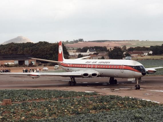 A white airplane with an orange stripe parked on a runway.