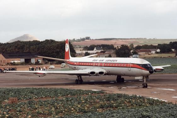 A white airplane with an orange stripe parked on a runway.
