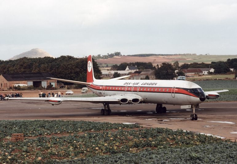 A white airplane with an orange stripe parked on a runway.