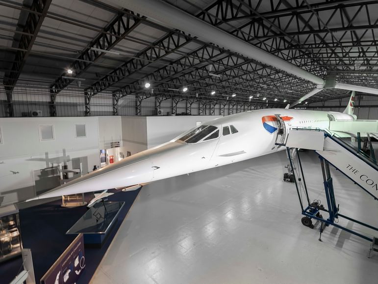 Concorde airplane with long pointed nose in a black and grey hanger