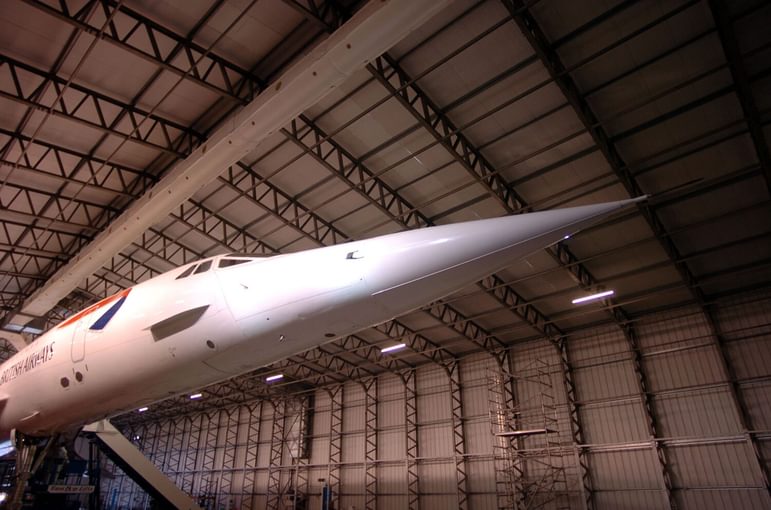 Partial view of the Concorde in an aircraft hangar, focusing on its long nose.