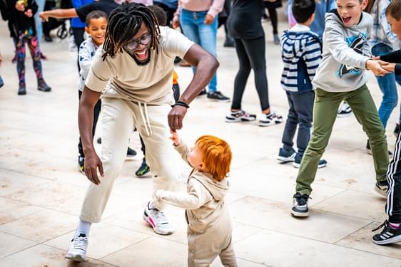 An adult and toddler dancing in a large group of people.