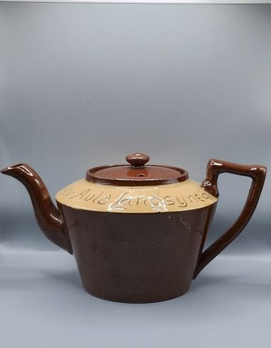 A Brown and yellow teapot with auld lang syne inscribed around the lid.