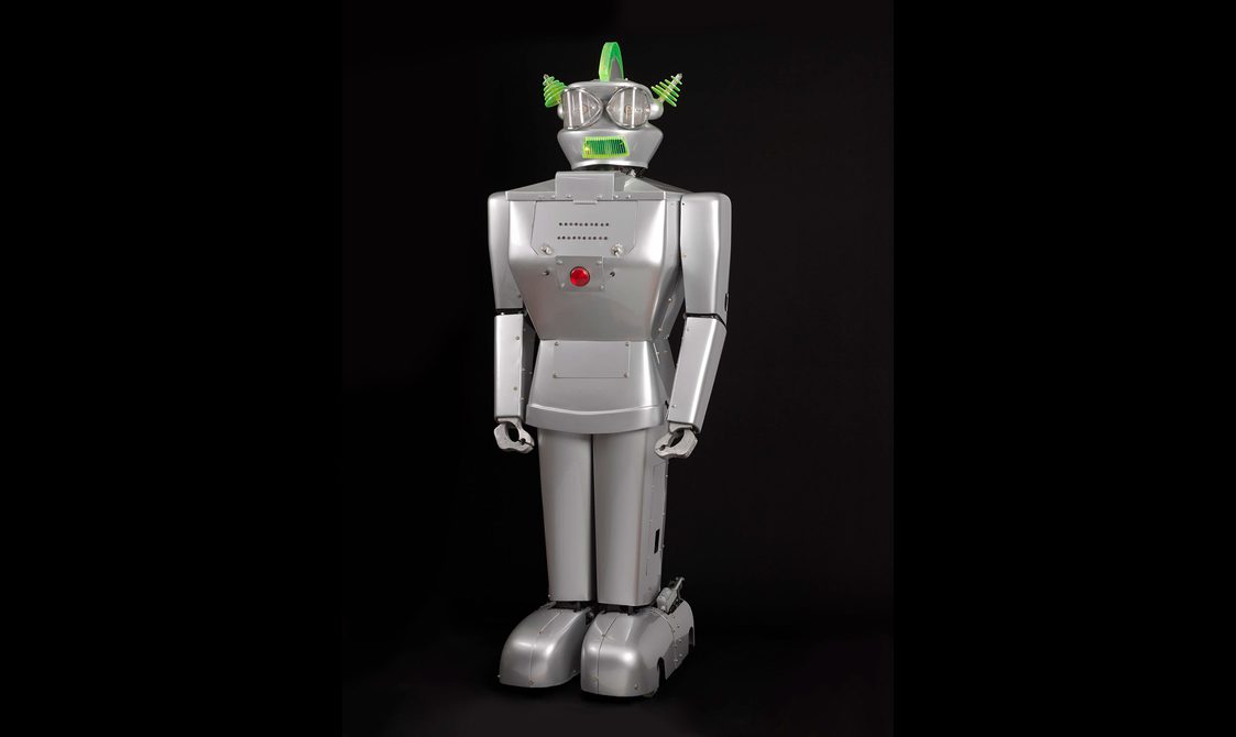 A silver robot with a red button in the middle of its chest.