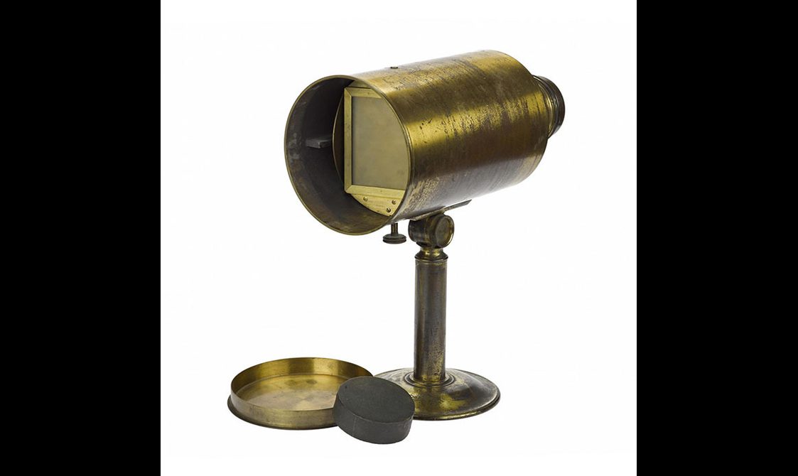 A brass daguerrotype camera on a stand with a cylindrical body.