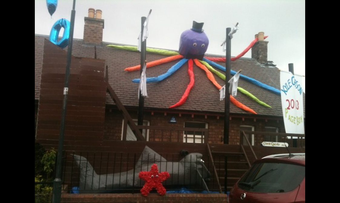 A cottage decorated in a sea theme - a large colourful octopus sits on the roof, with a shark and starfish in the front garden