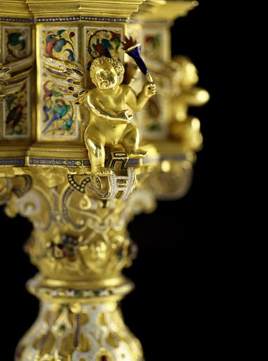 A gold cherub decorates the foot of an ornate cup
