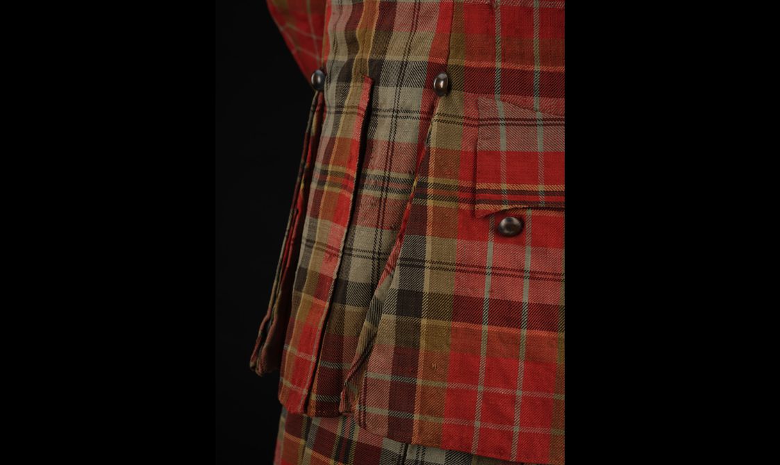 Detail of a red tartan coat with button details.