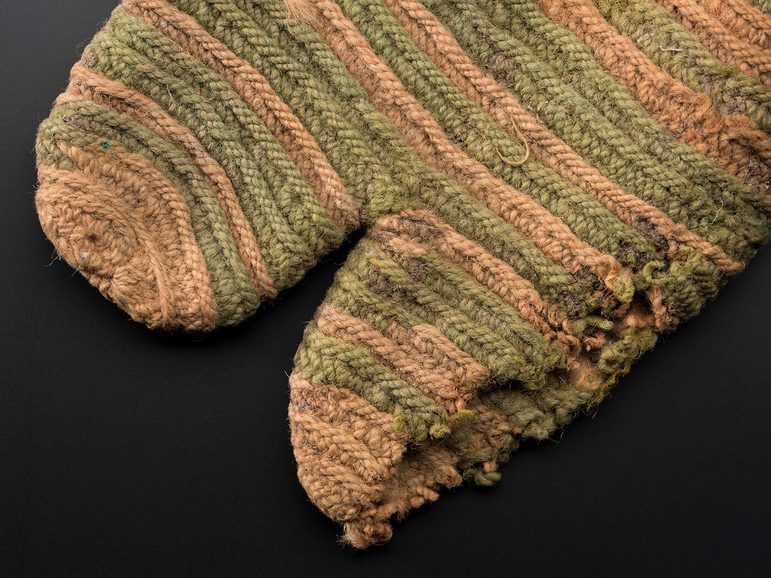 Detail of a faded striped knitted sock with a split toe design and various holes