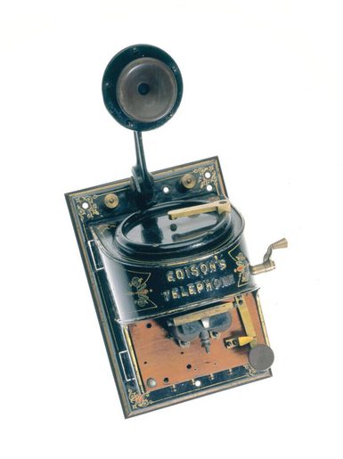 An early telephone which is a black rectangle with a round protruding part. It says Edison's telephone.