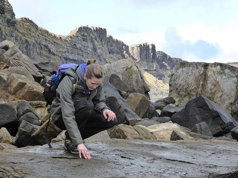 Dr Elsa Panciroli crouching on a large rock.