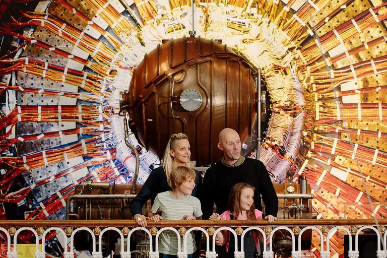 A family of four standing on a balcony in front of a CERN collider.