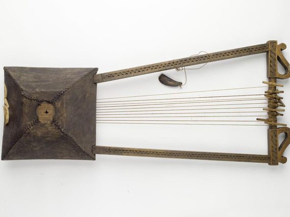 Wooden trapezoid prism shaped box with three U shaped wooden sticks attached horizontally to the box. Numerous thread strings attached between the box and the vertical stick.