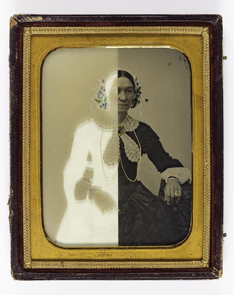 A black and white image of a woman in Victorian dress with half of the image in a white negative. The photograph has a gold border and wooden frame.