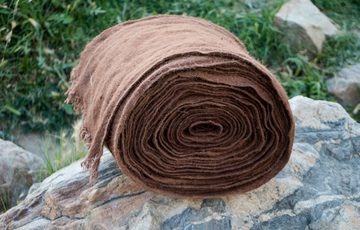 A large roll of brown wooled fabric resting on a jagged grey rock.