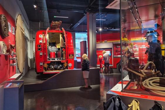 Visitors looking at fire safety items on display in a museum gallery