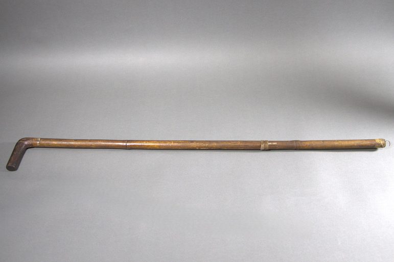 A long wooden stick, with a short straight end that juts out at a 90 degree angle.