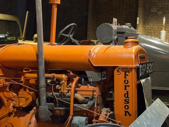 The front end of an orange coloured tractor.