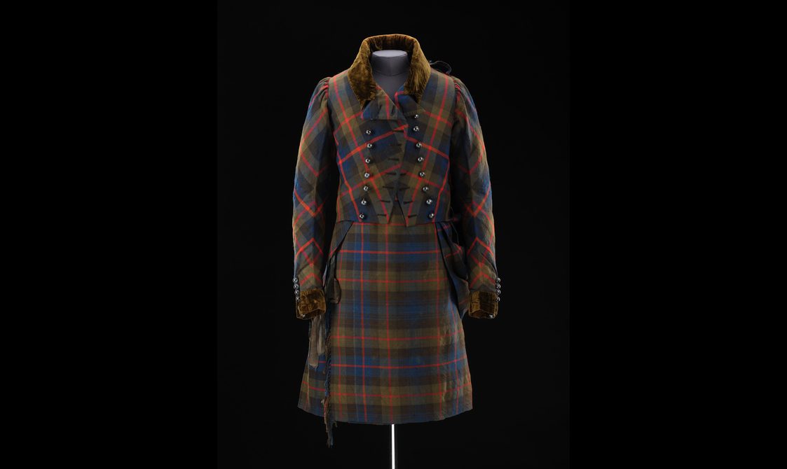 A mannequin wearing a navy, green, and red tartan kilt and matching jacket.