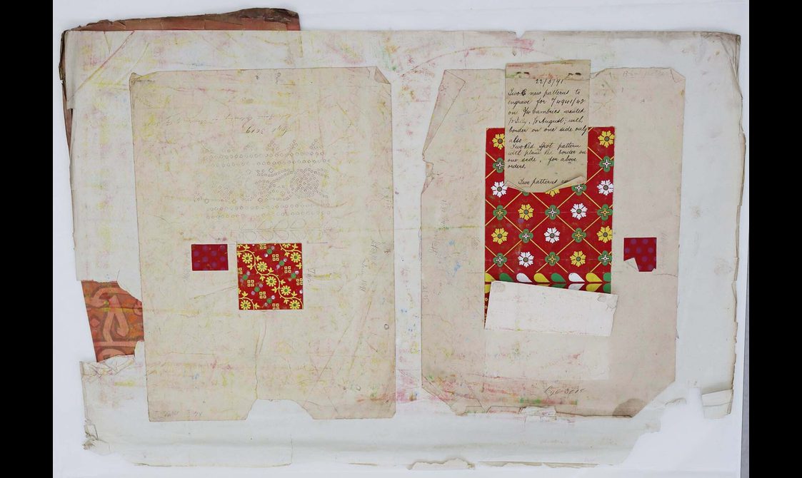 A sheet of paper, featuring patches of decorative red and yellow patterns, is laid out flat