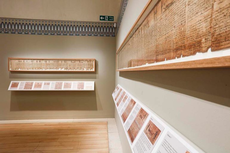 A display in a museum of framed ancient scrolls mounted on a wall.