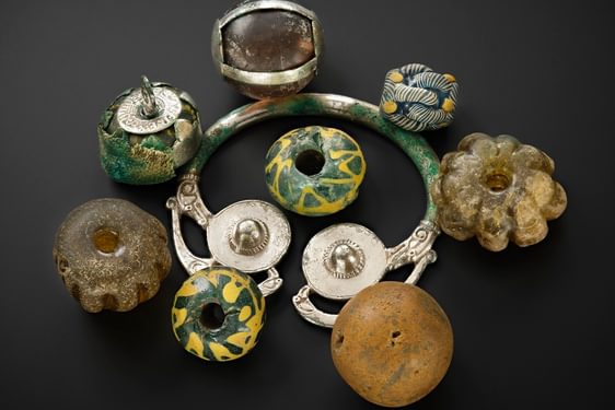 A group of objects made of silver, stone, and coloured stones, all sitting on a black background