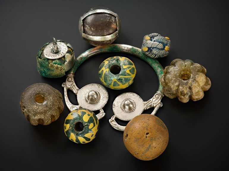 A group of objects made of silver, stone, and coloured stones, all sitting on a black background