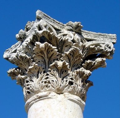 The top of a decorated Roman column against a blue sky