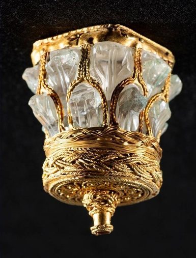 A highly decorated crystal and gold object that looks like the top of a Roman column