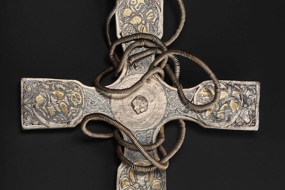 A metal pectoral cross with intricate carved designs on the arms.