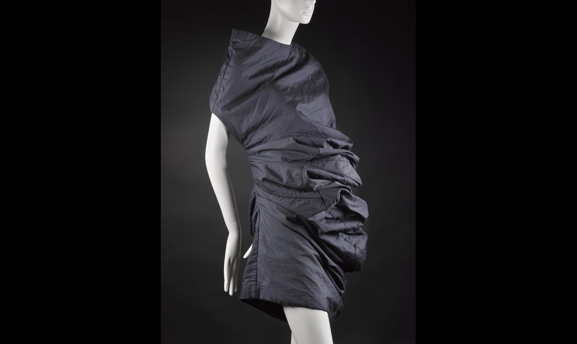A ruffled black dress on a mannequin with bumps created by excess fabric.
