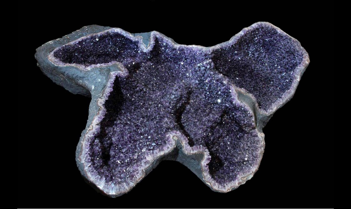 The interior of an amethyst geode with dark purple crystals.