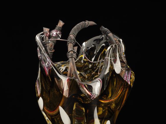 A glass sculpture of multiple colours resembling a shape of a cylinder with copper wires.