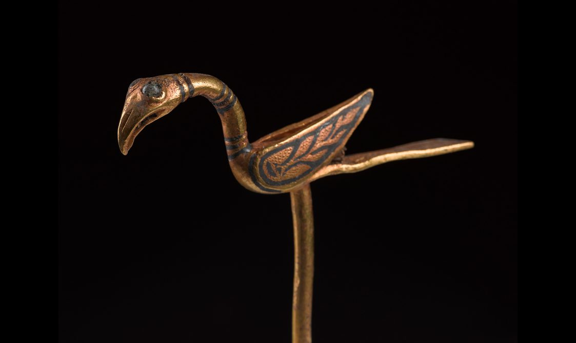An elaborate gold pin in the shape of a bird.