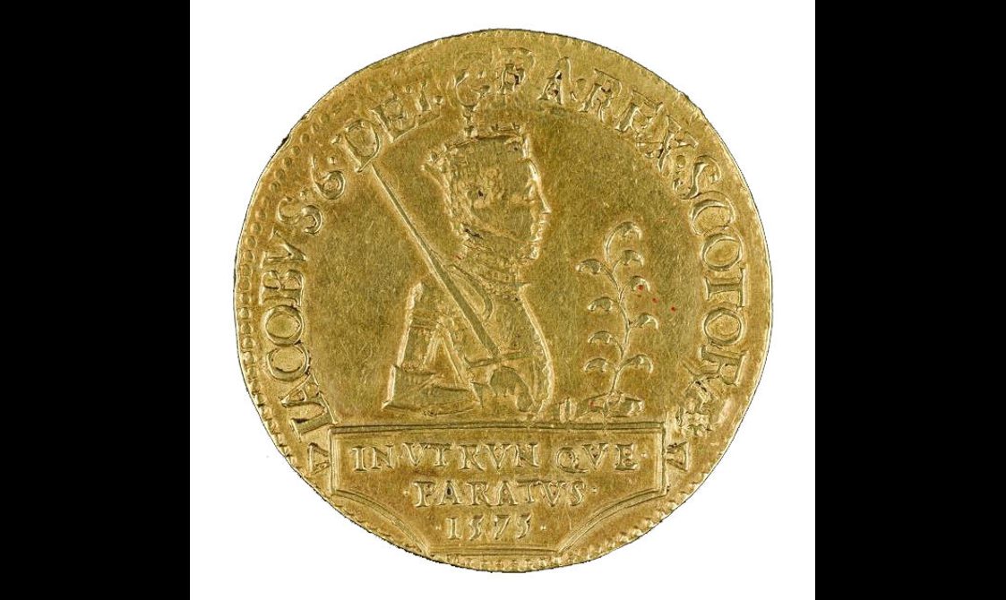 A gold coin with a king in profile and letters around the edge.