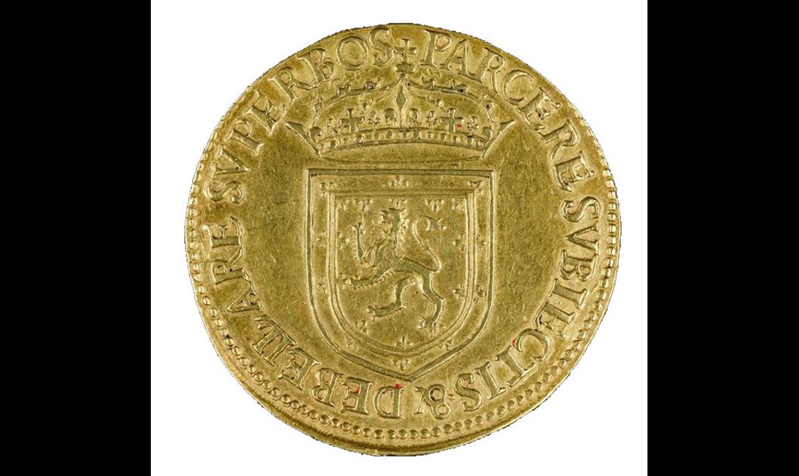 A gold coin with a royal crest and crown with writing around the edge.