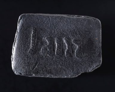 A small black rectangular stone, with relief lettering that says 'I am'.