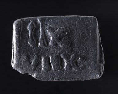 A small black rectangular stone, with relief lettering that says 'the vine'.