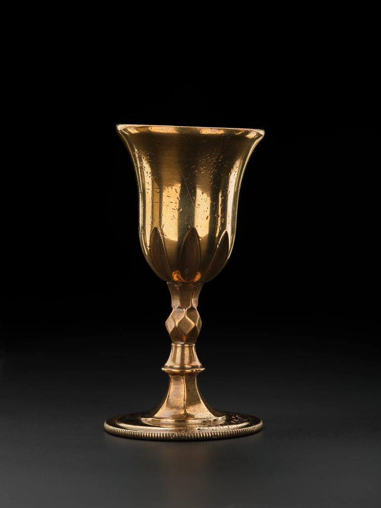 A golden chalice, against a black background.