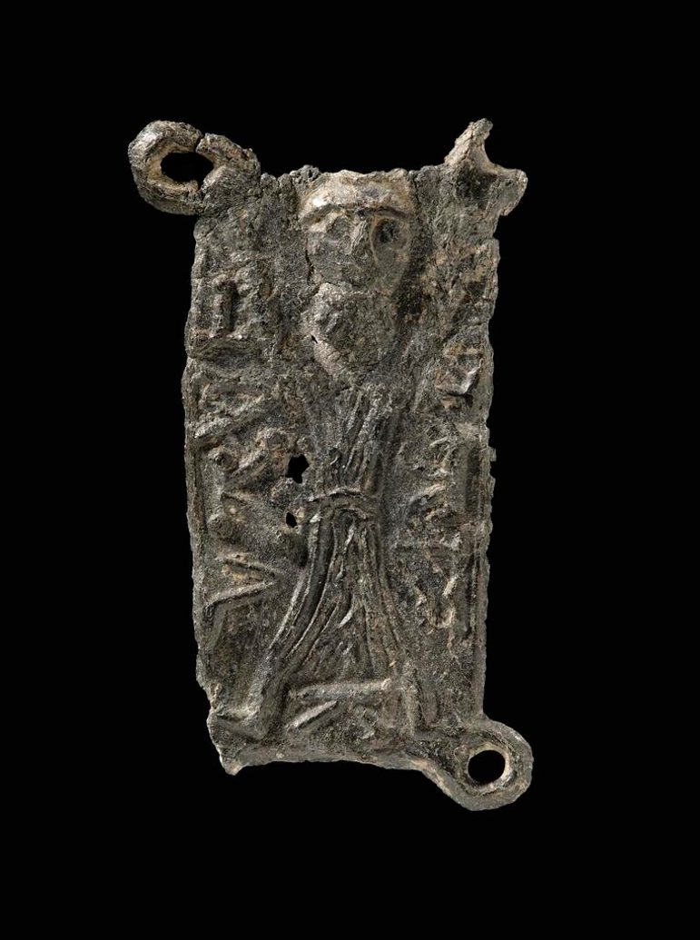 A square, metal badge with broken ringlets. There's a relief casting of St Andrew on his cross designed on the front.
