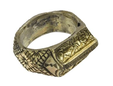 A gold finger ring, which is carved with religious imagery.