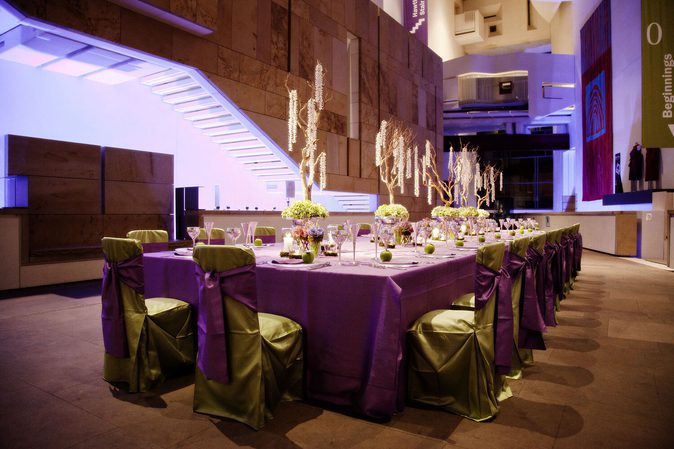 A long table set for dinner in Hawthronden Court at the Naitonal Museum of Scotland. The space has high ceilings and grand modern architecture.