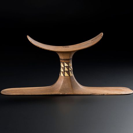 A wooden stand om inlaid with a brown and ivory pattern, with a curved panel