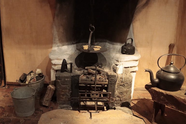 A classic rural hearth setting, showing a kettle and buckets around the hearth.