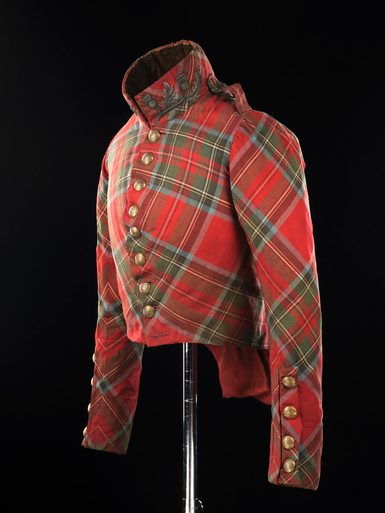 A mannequin wearing a short tartan jacket with gold buttons fastened along the front up to a turned up collar.