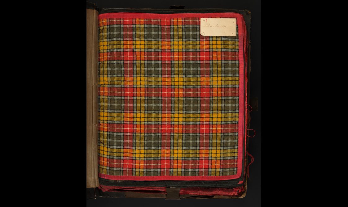 A swatch of yellow, red, and green checked tartan with a label sewn on the top right corner.