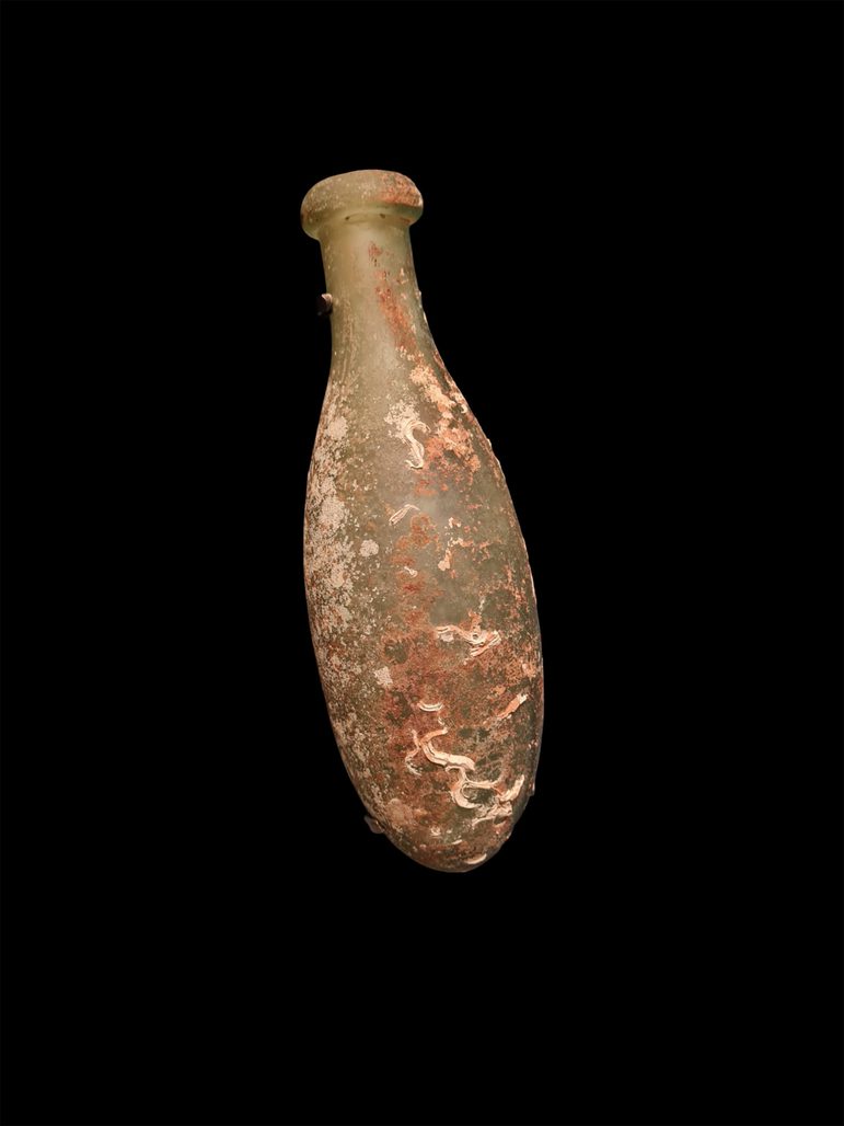 A small green glass bottle with an oval body covered in marine growths