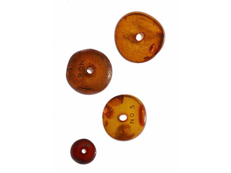 A group of four amber beads with centre holes for suspension.