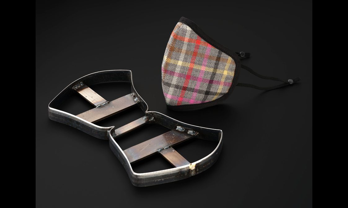 A tartan facemask and a steel press knife against a black background.