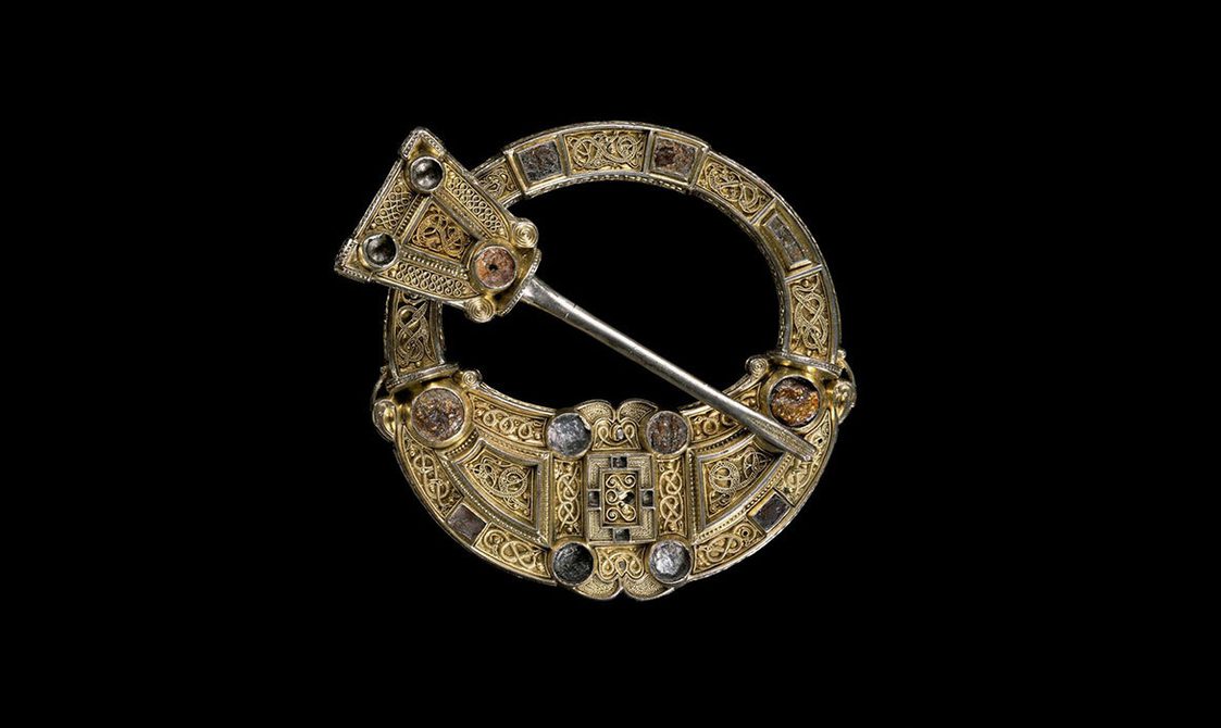 A small circular gold brooch in celtic style.